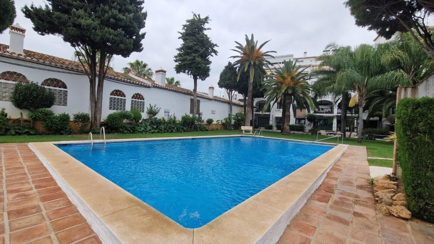Piscina comunitaria rodeada de césped y jardines maduros en la urbanización Puebla Lucía de Fuengirola